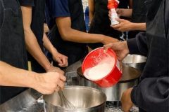 Group preparing traditional French crepe batter during a cooking class in Paris.
