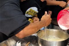 Participant mixing crepe batter during a hands-on crepe making class in Paris.