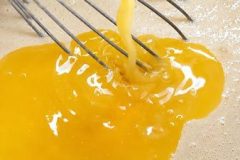 Adding beaten eggs to crepe batter during a traditional Breton crepe recipe preparation.