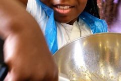 Enfant préparant la pâte à crêpes lors d'un atelier de cuisine à Paris.