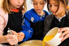 Enfants préparant une pâte à crêpes pendant un atelier familial à Paris.