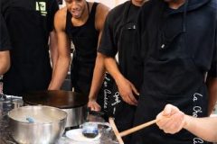 Groupe d'étudiants apprenant à réaliser une crêpe sur billig à Paris.