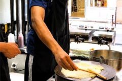 Participant réalisant une crêpe sur une billig lors d'un cours à Paris.